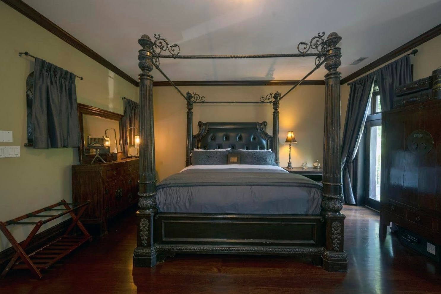 A bedroom with a four poster bed and a dresser