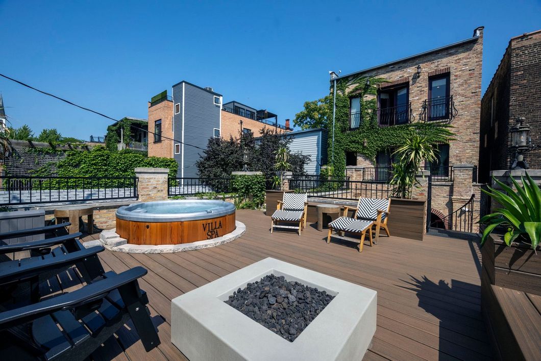 A rooftop deck with a hot tub and a fire pit.