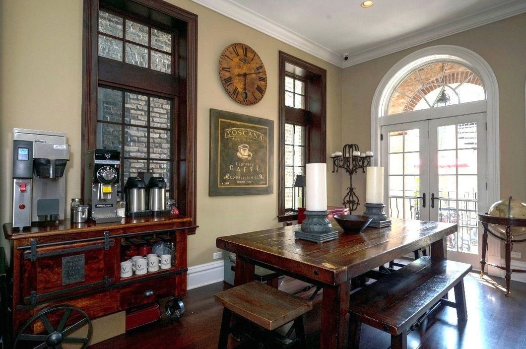 A dining room with a wooden table and benches and a clock on the wall.