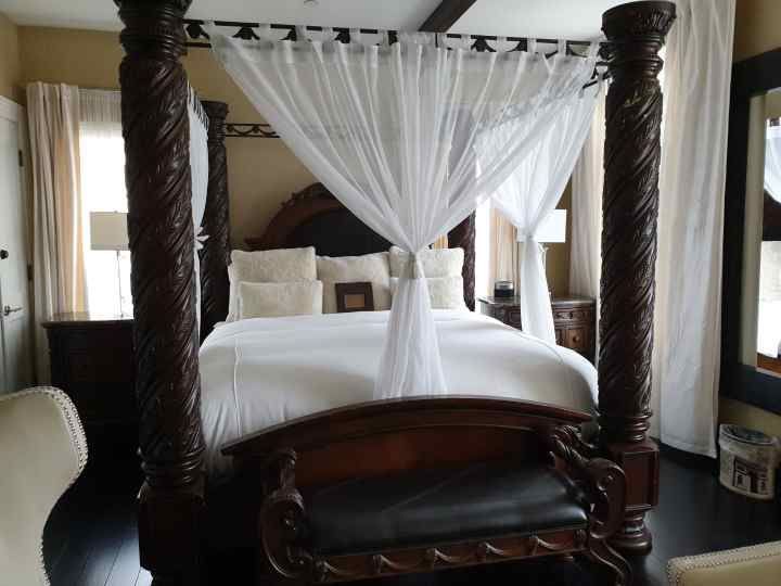 A bedroom with a canopy bed and a chair