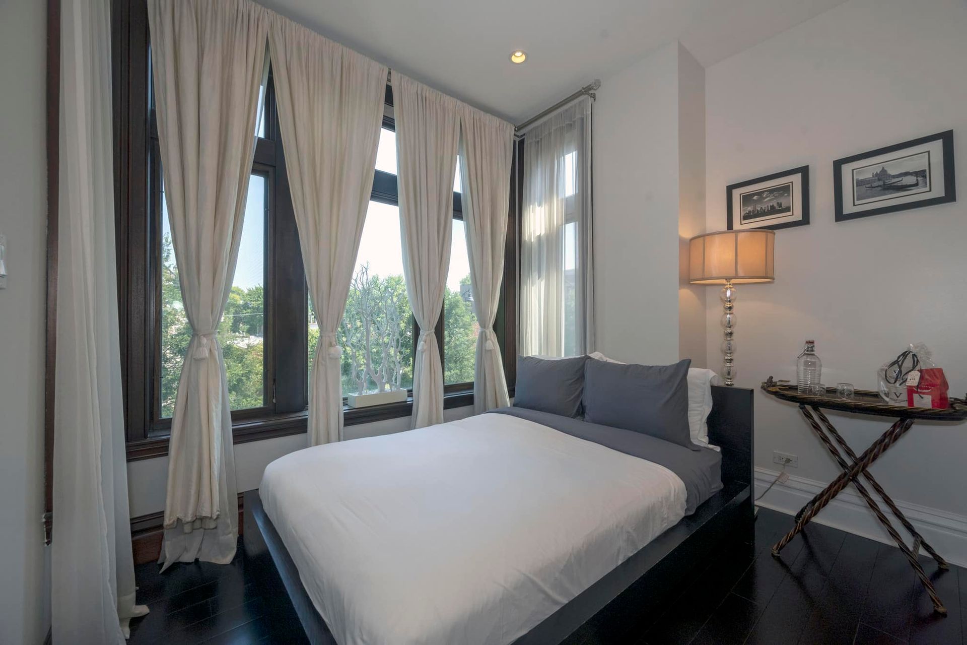 A bedroom with a king size bed , two windows and a table.