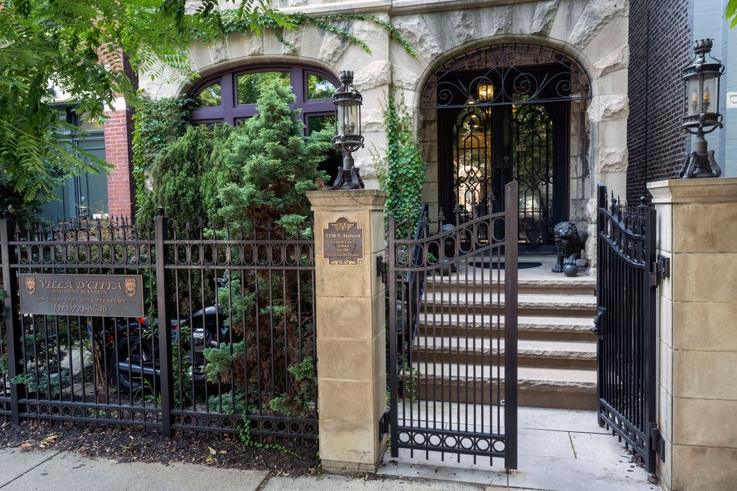 The front of a house with a wrought iron fence and gate.