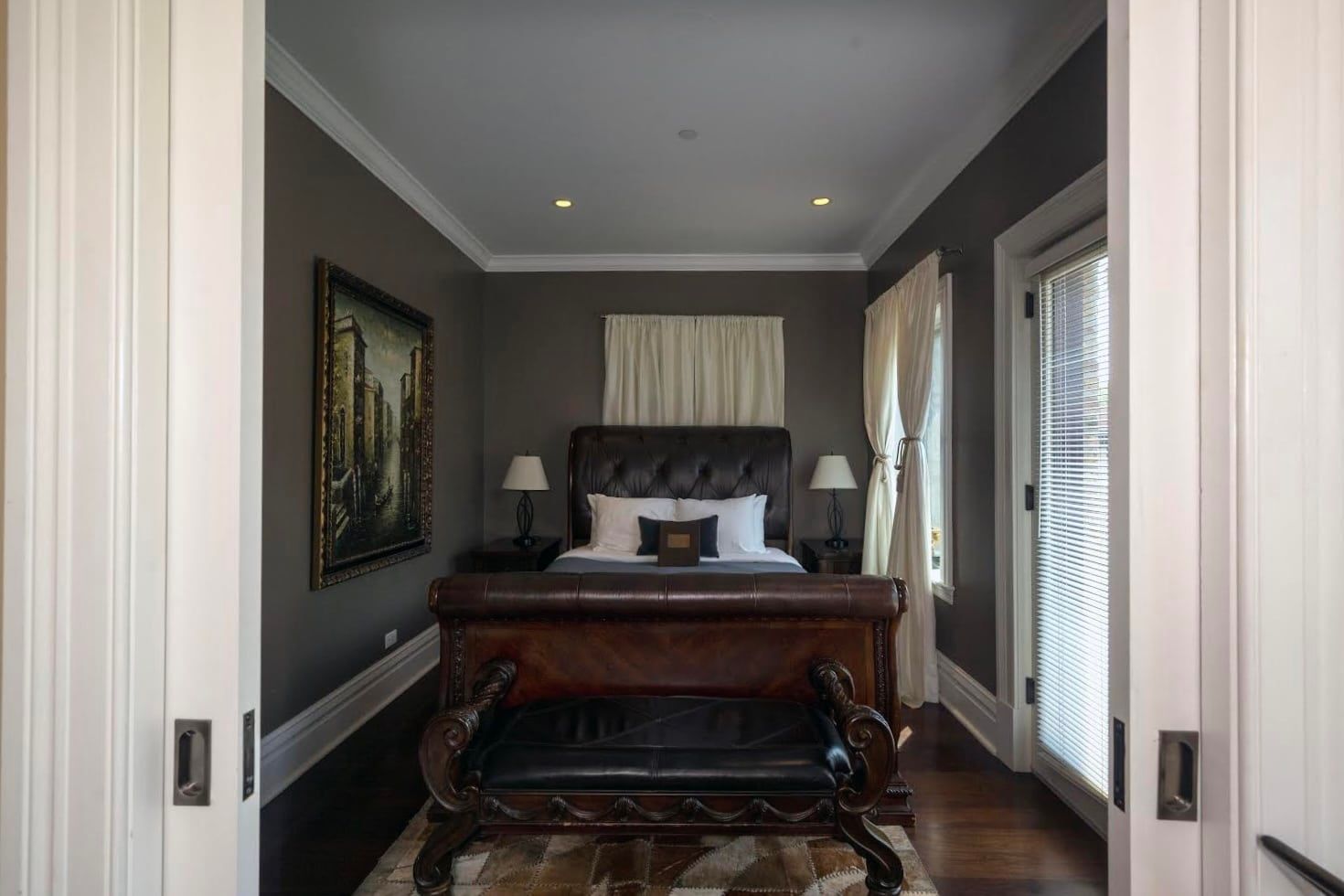 A bedroom with a bed , bench and sliding glass doors.