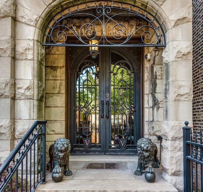 Two statues of lions are in front of a wrought iron door