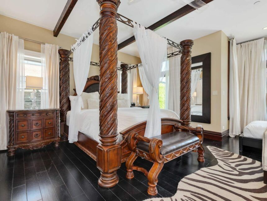 A bedroom with a four poster bed and a zebra print rug.