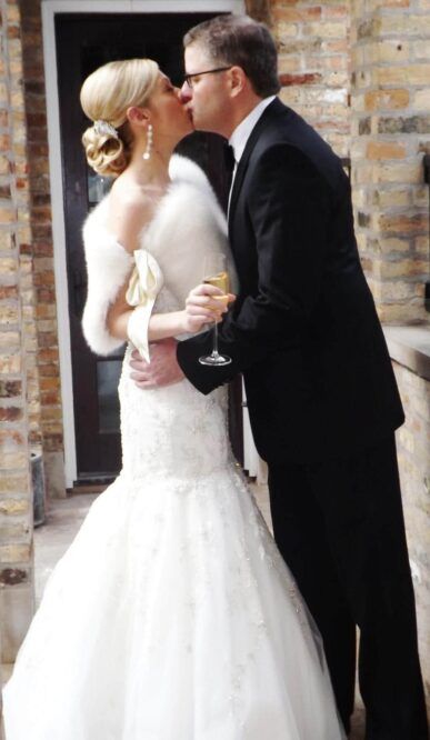 A bride and groom kissing in front of a brick building