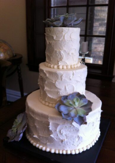 A white wedding cake with a blue flower on top
