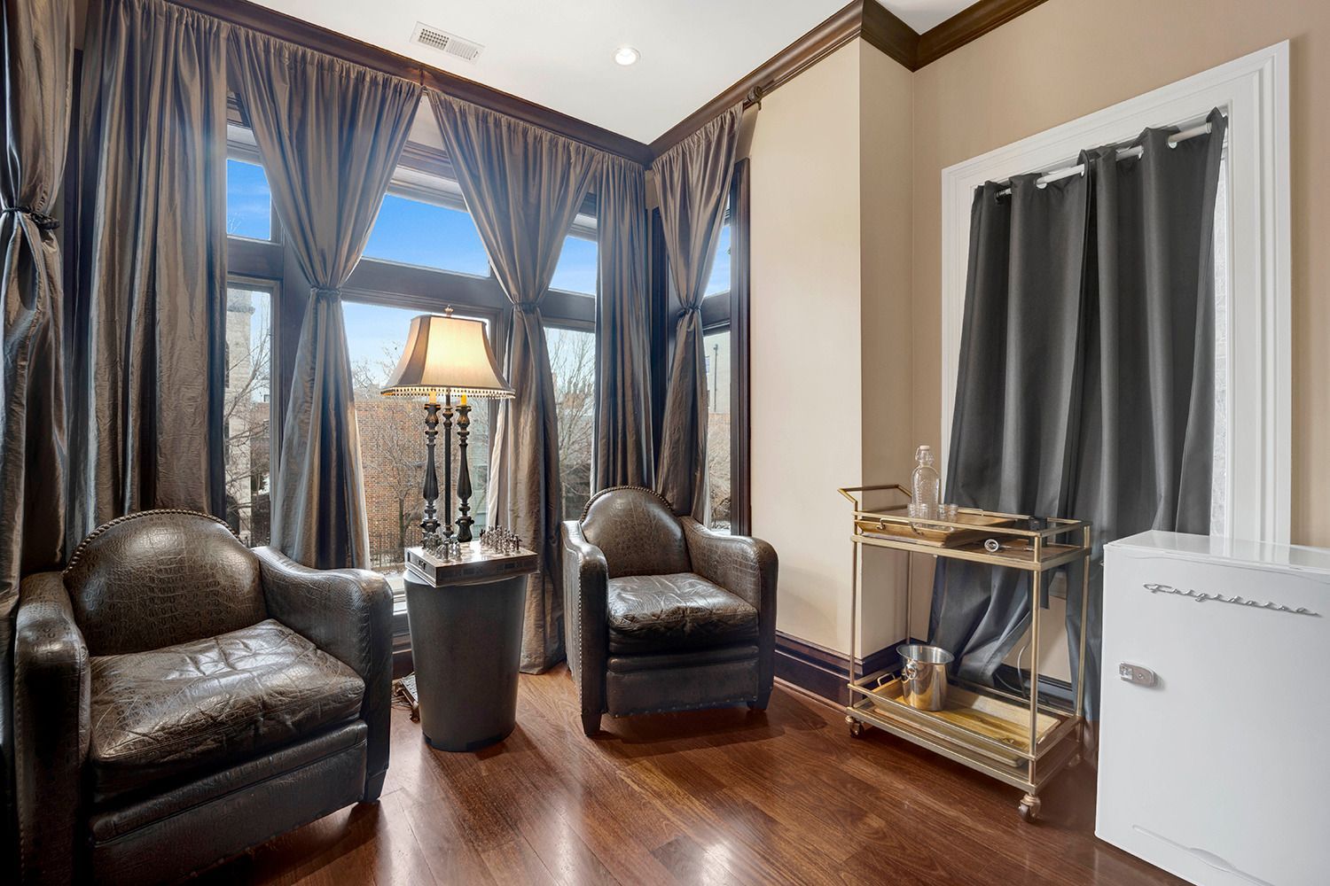 A living room with two chairs and a bar cart.