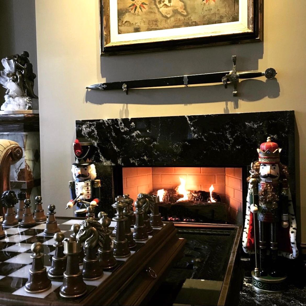 A fireplace with a picture above it and a chess board in front of it