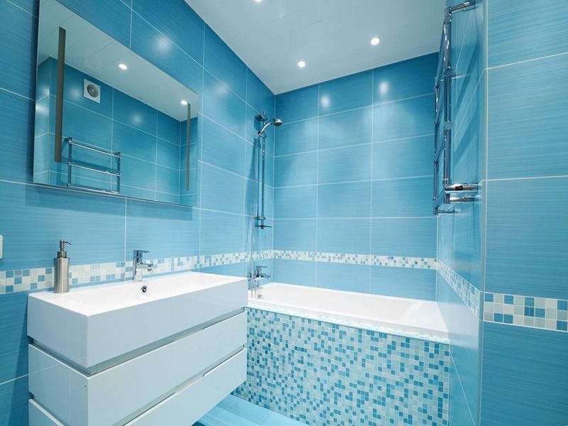 Un bagno ristrutturato con piastrelle blu, un lavandino e una vasca da bagno.