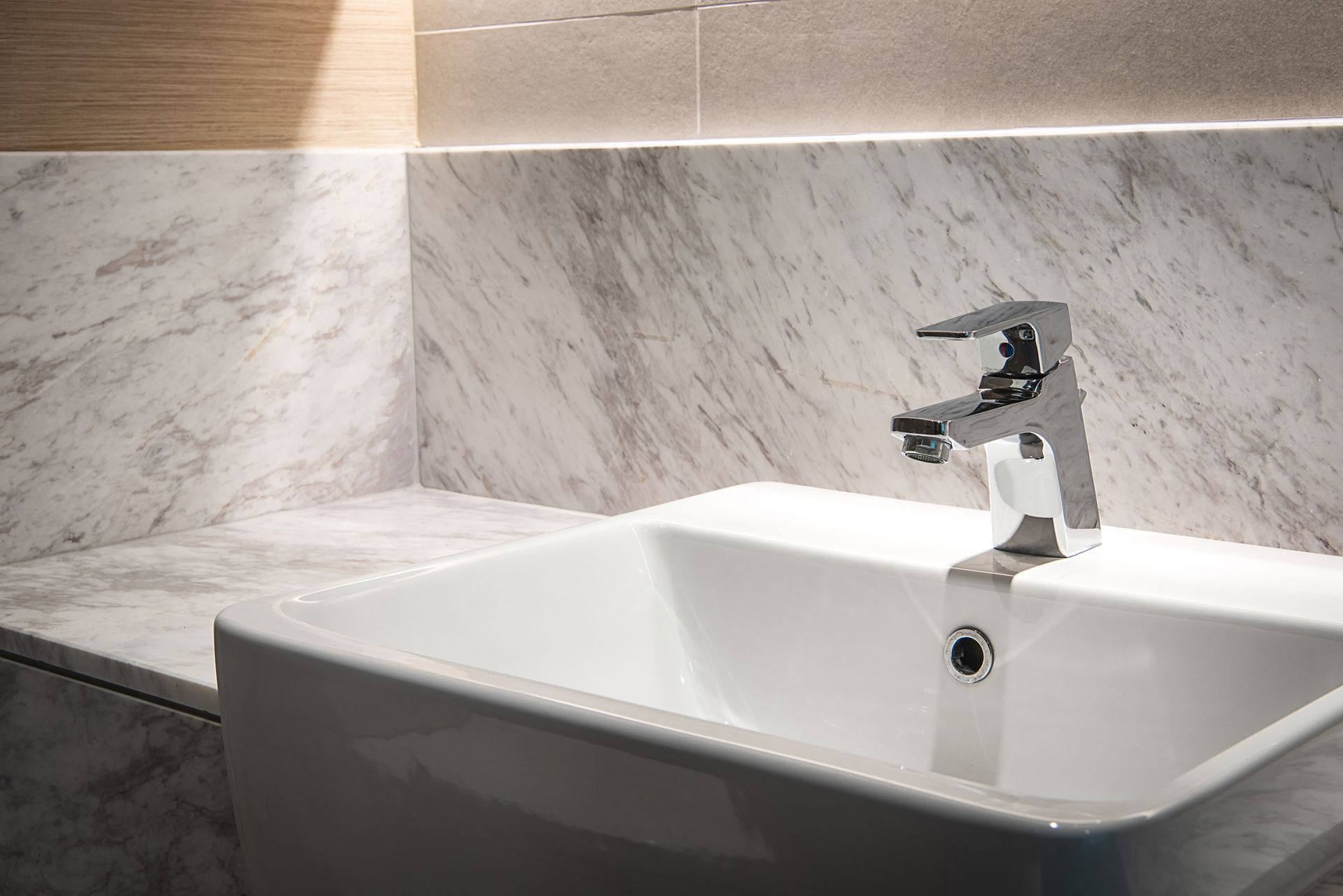 Un lavandino del bagno con rubinetto cromato e piano in marmo.