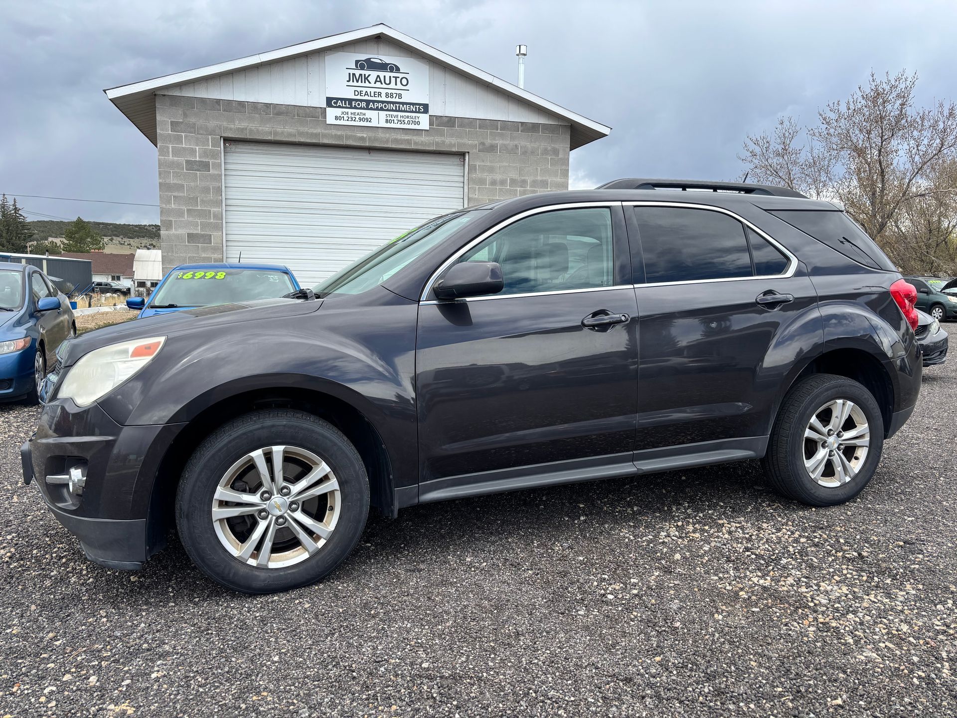 Dark gray SUV parked on gravel in front of a white garage building