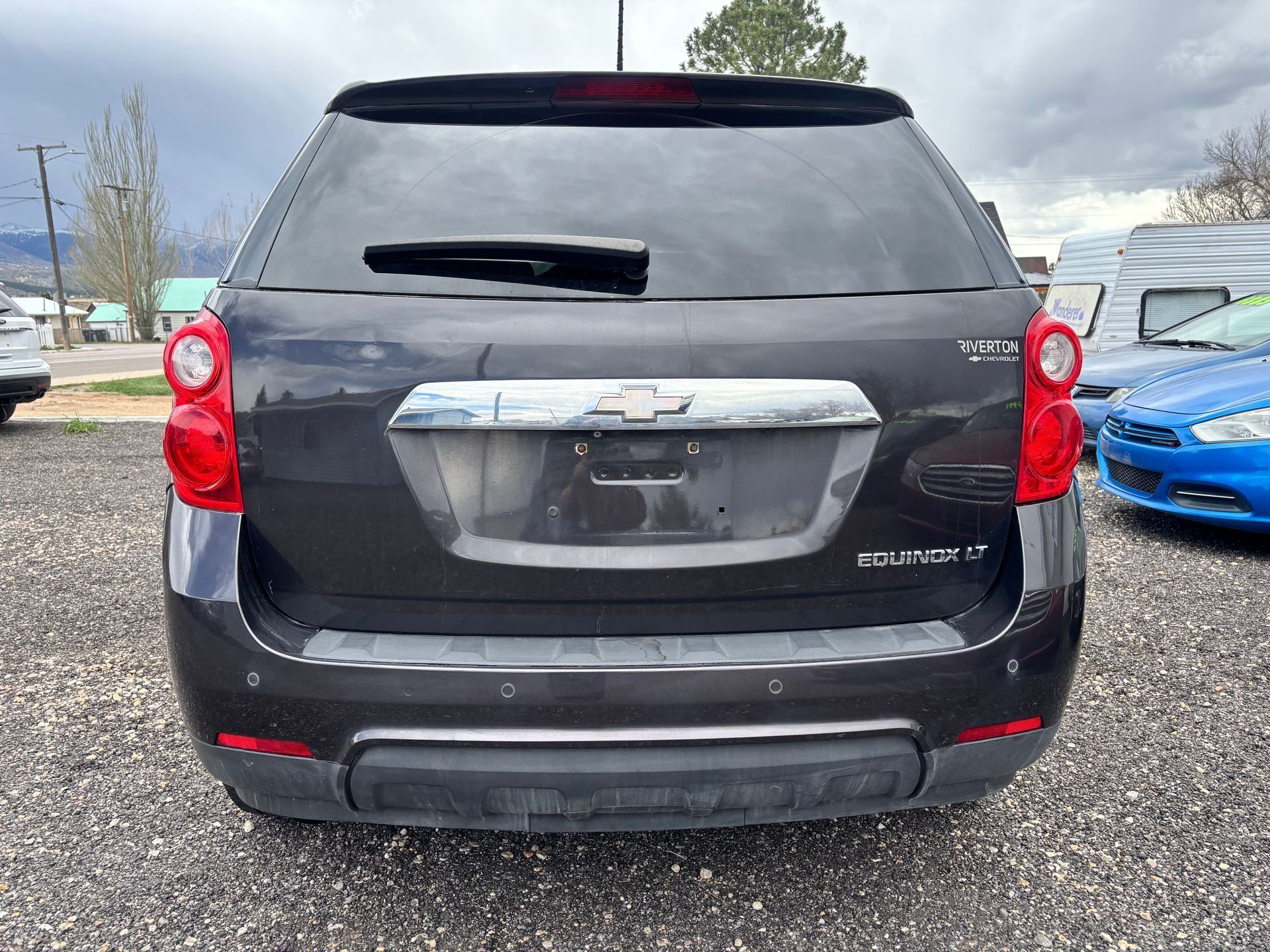Rear view of a black Chevrolet Equinox SUV parked in a lot, with a blue car beside it.