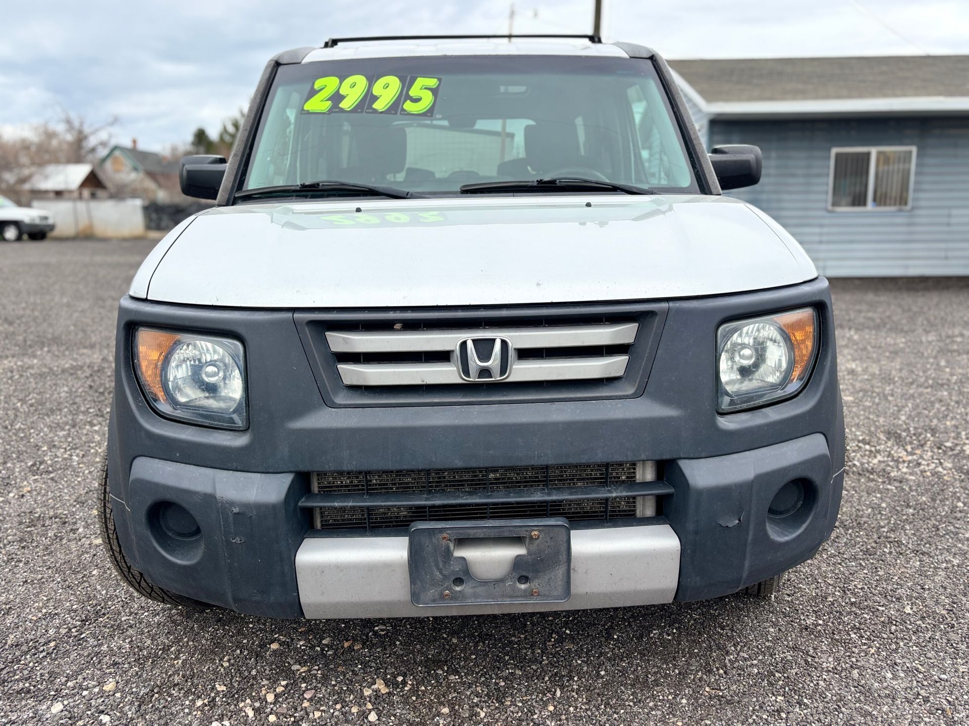 Front view of a white Honda Element with a $2995 windshield sign, parked outdoors.
