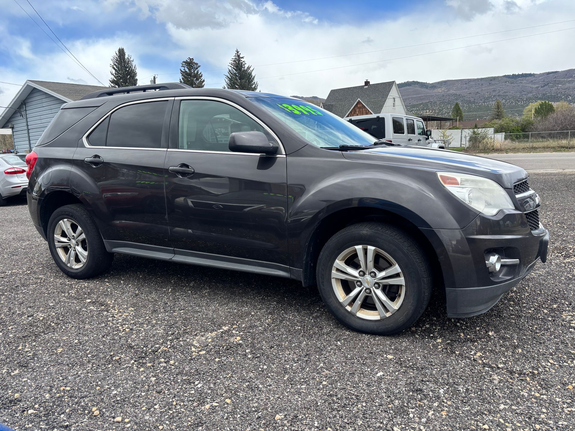 Black SUV parked on a gravel lot with a house and mountains in the background