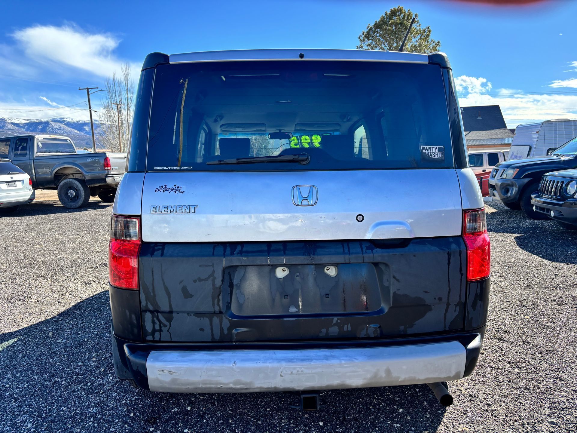 Rear view of a black and white SUV parked in a lot on a sunny day