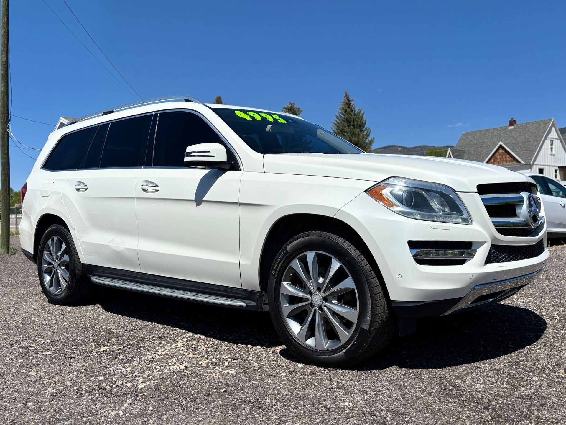 White Mercedes-Benz SUV parked on gravel under a clear blue sky