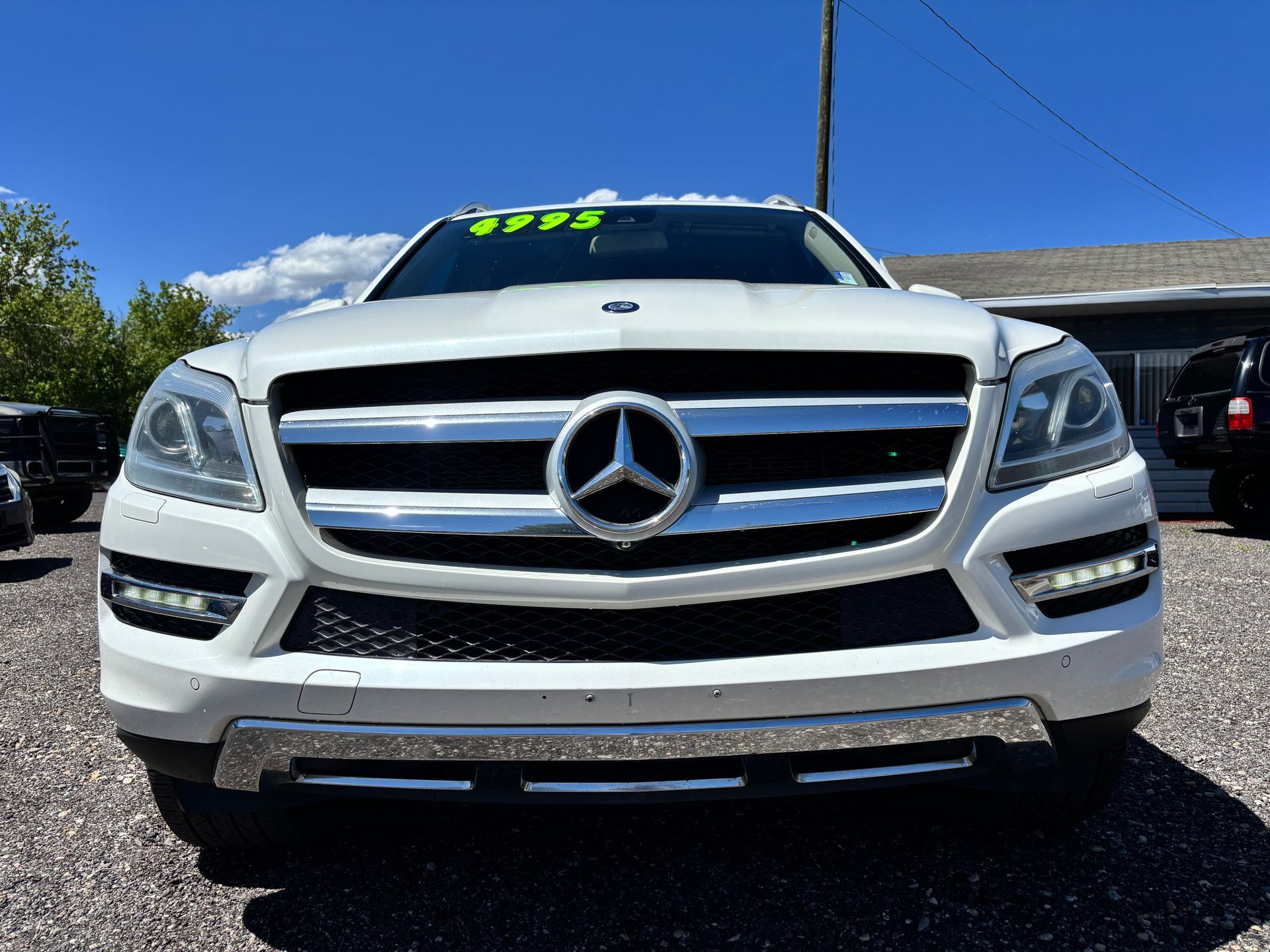 Front view of a white Mercedes-Benz SUV parked outdoors on a sunny lot