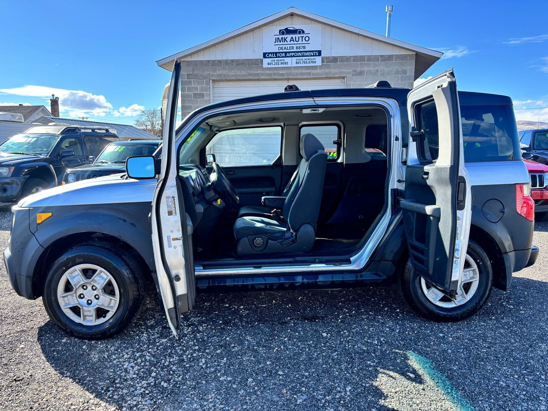 Side view of a white-and-blue van with both side doors open, parked outside a building.