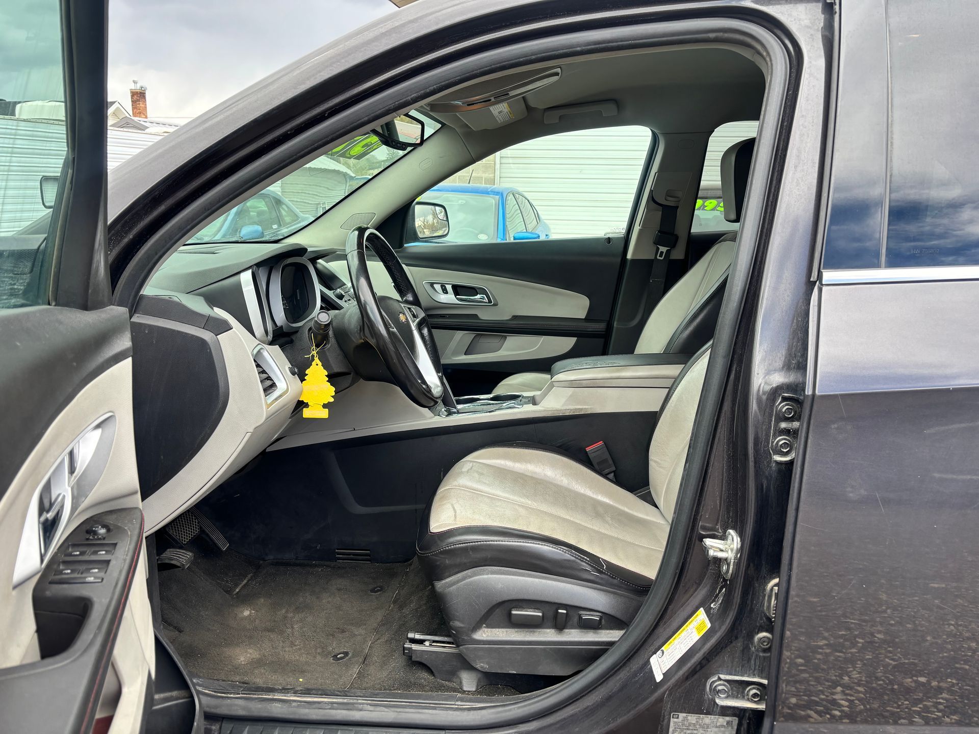 Car interior with front and rear doors open, showing gray seats and dashboard.