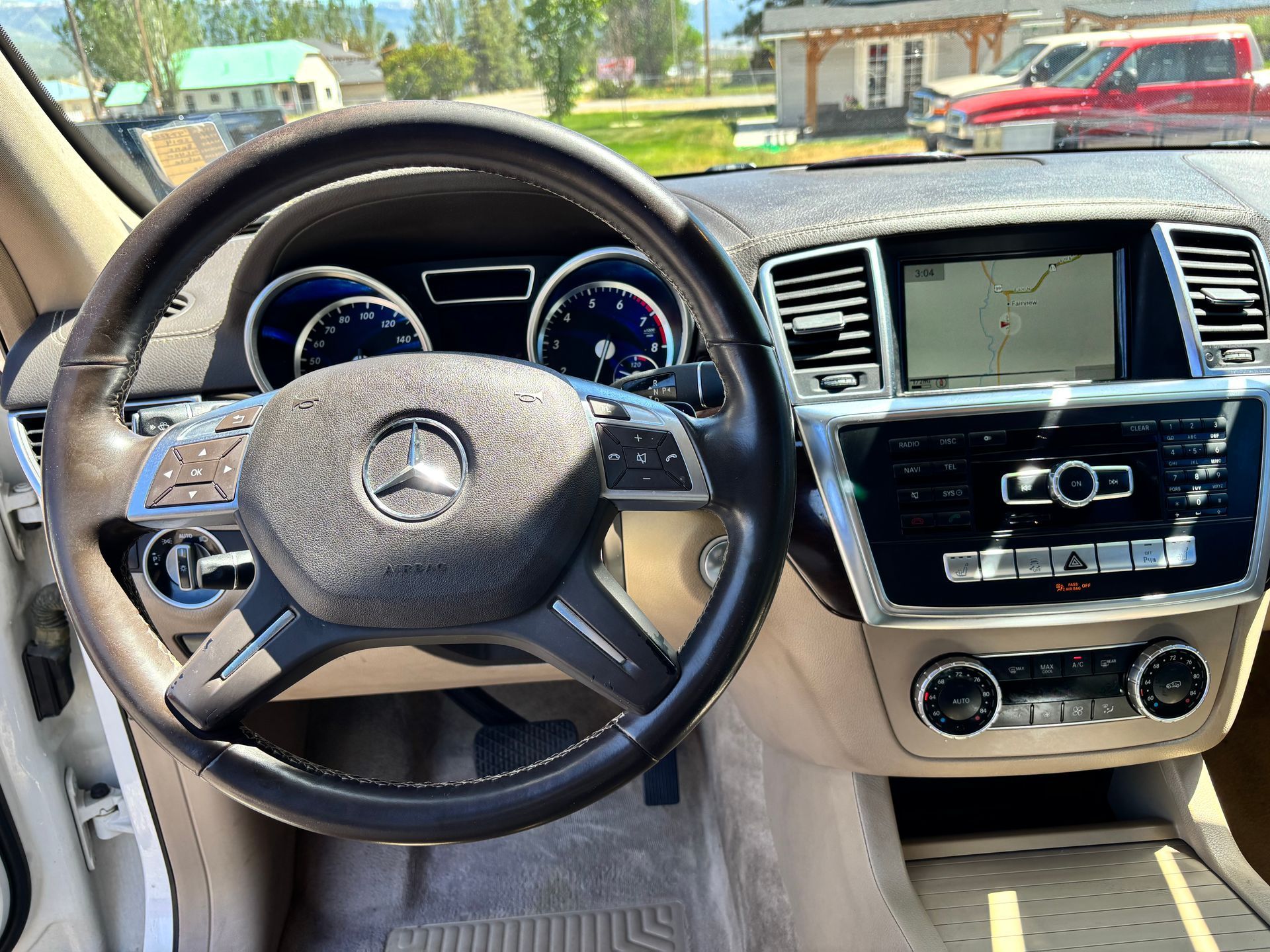 Mercedes-Benz interior with steering wheel, dashboard, and center console in tan and black trim.