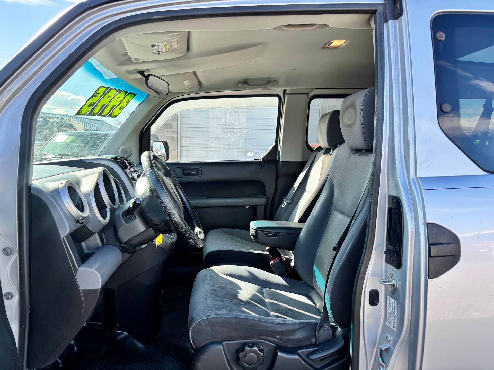 Open truck interior with gray seats, black dashboard, and windshield price tag