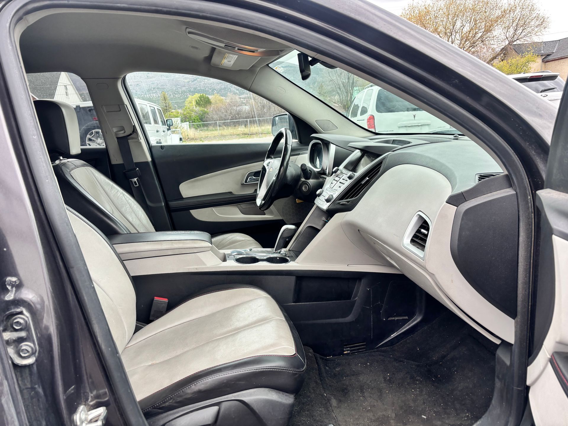 Black car interior with front passenger door open, showing gray seats and dashboard.