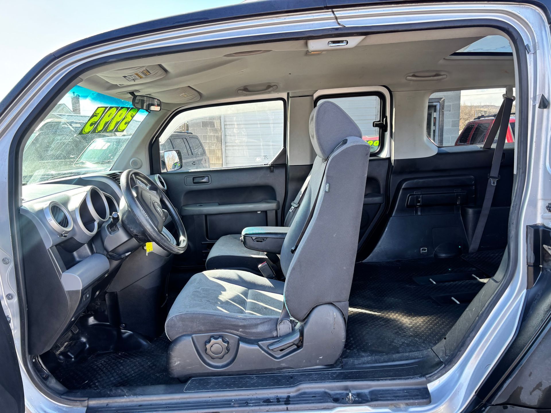 Open car driver-side interior with gray seats, dashboard, steering wheel, and open door.