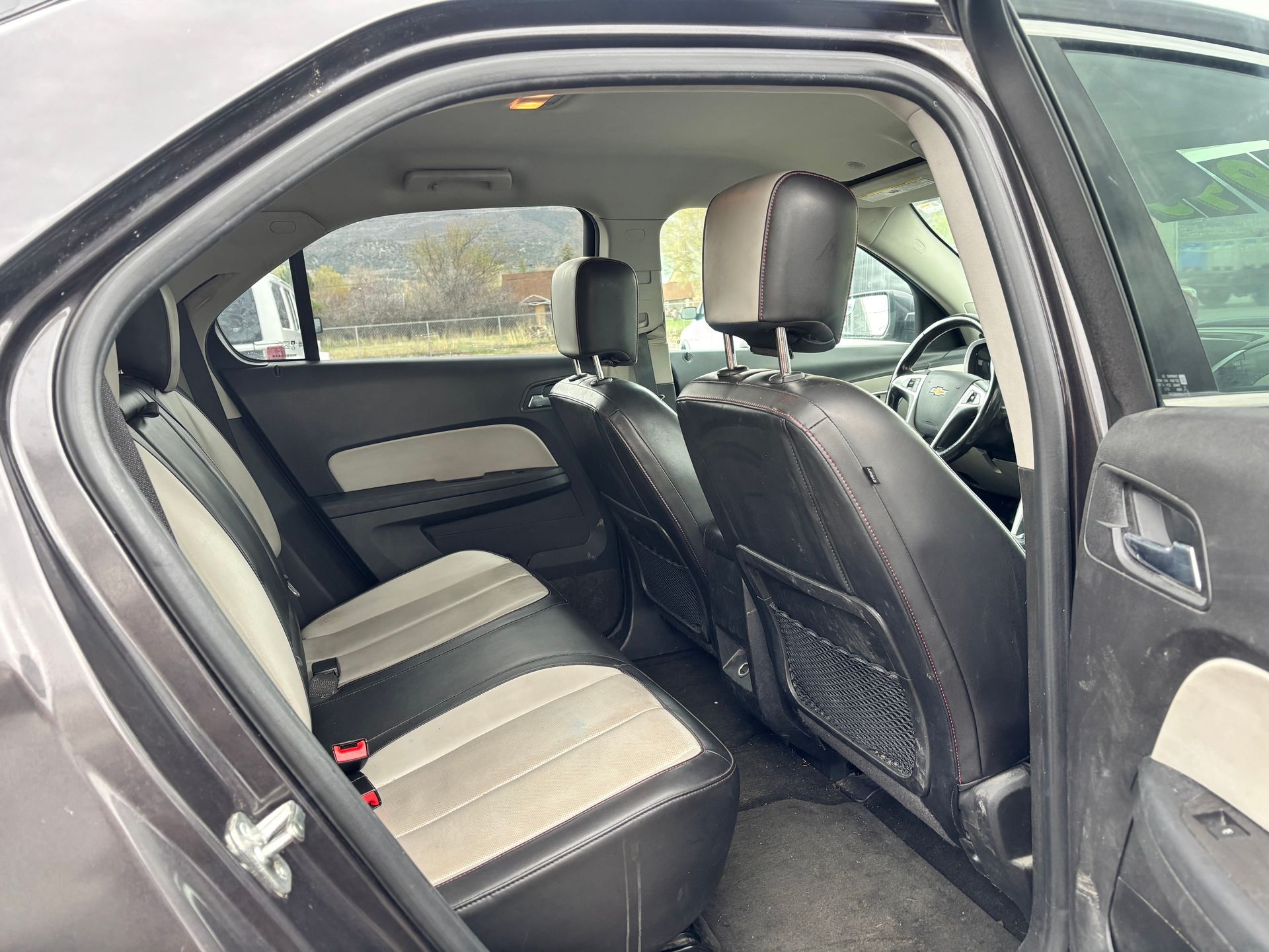 Open car door showing the rear seat interior with black and gray upholstery.