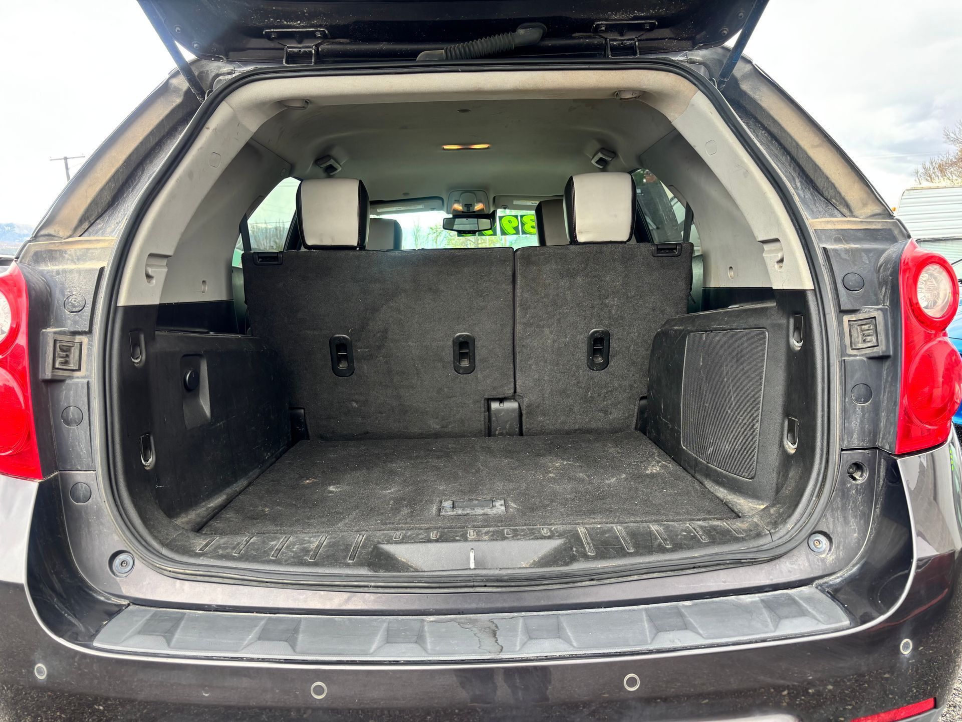 Open SUV cargo area with folded rear seats and a scuffed black interior.