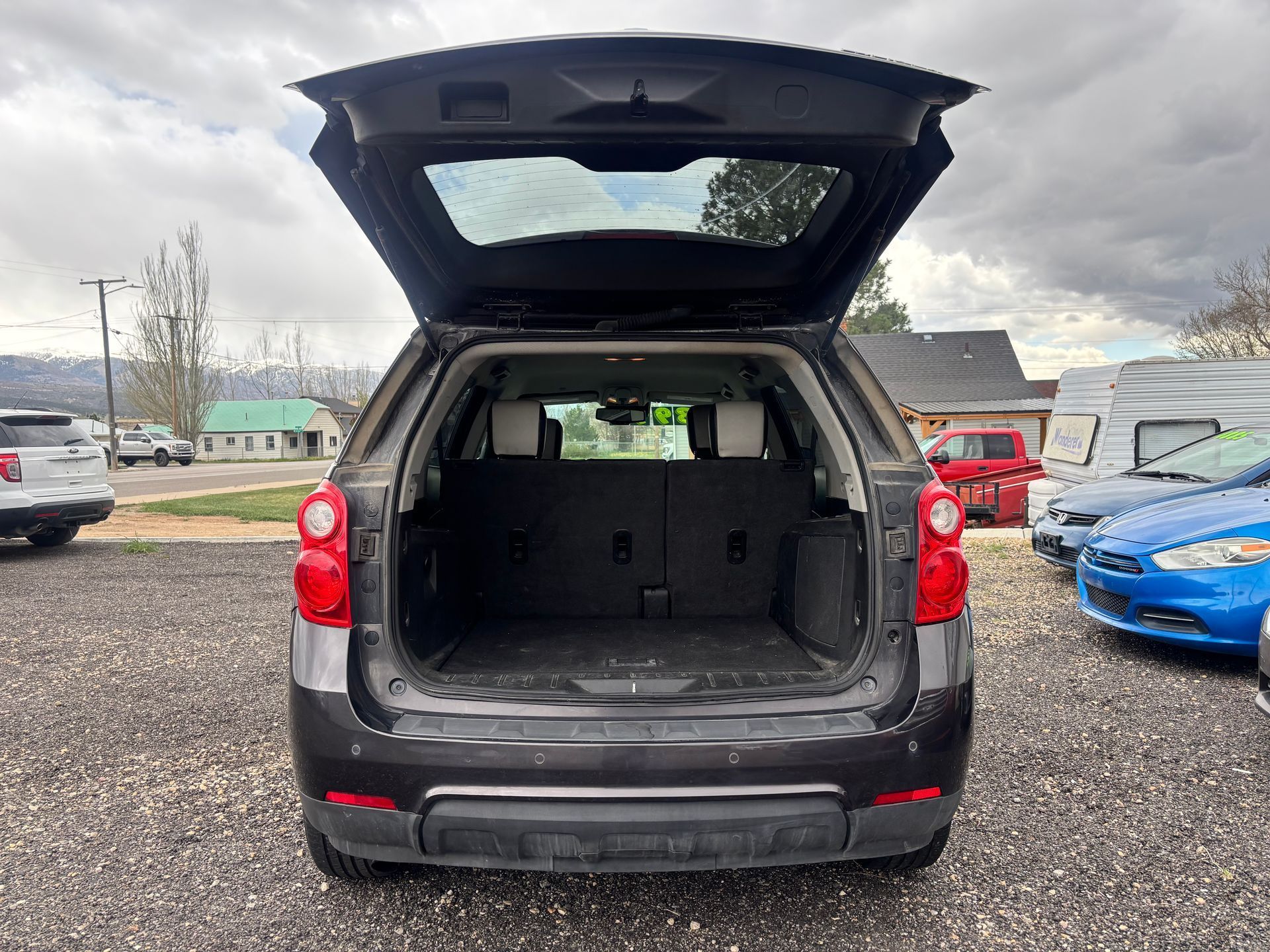 Open SUV cargo area with hatch raised in a gravel parking lot