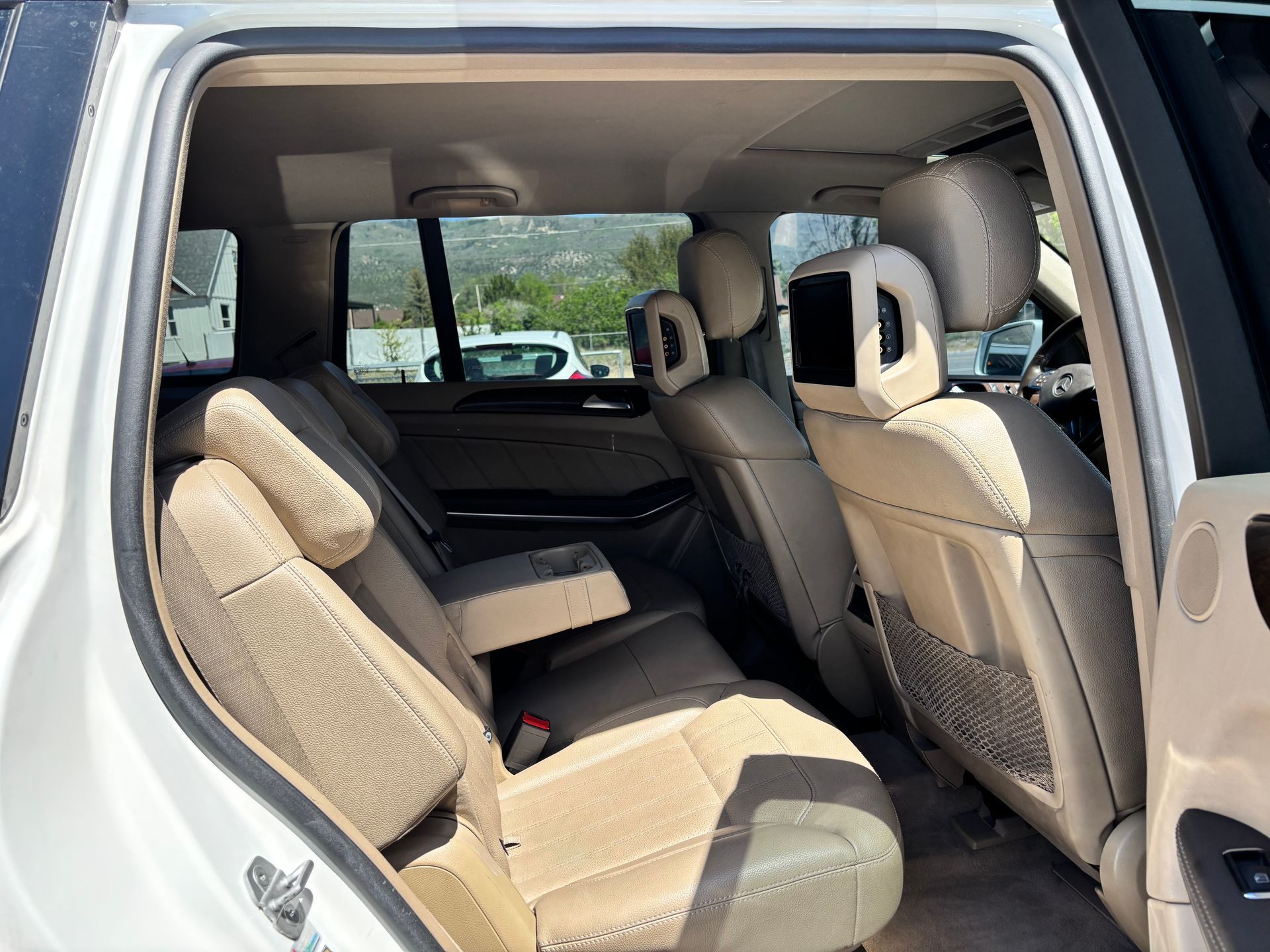 Open SUV rear seating area with beige upholstery and folded seats, viewed through the open back door