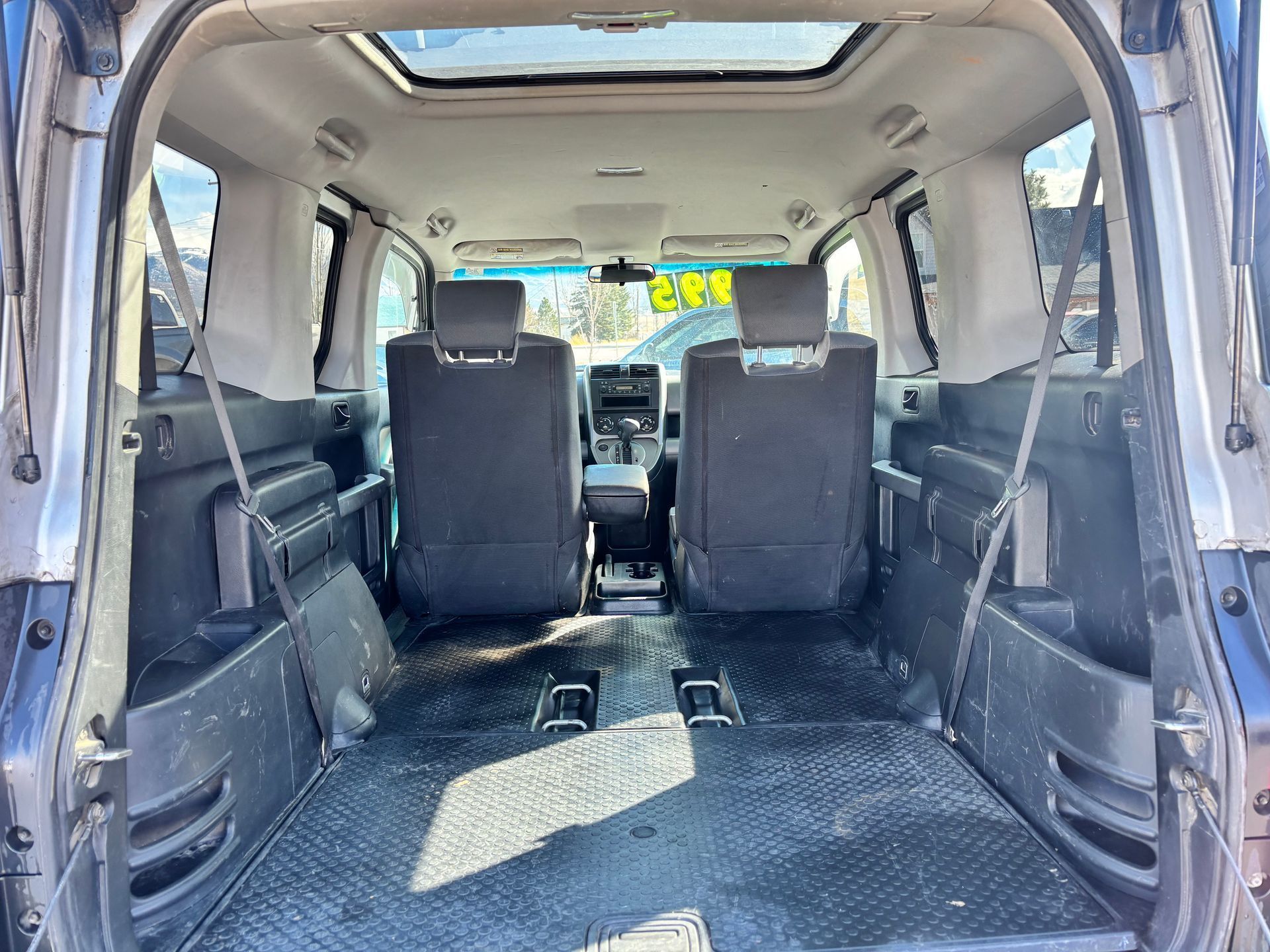 Empty van interior with black seats and rubber floor mats, viewed from the rear cargo area