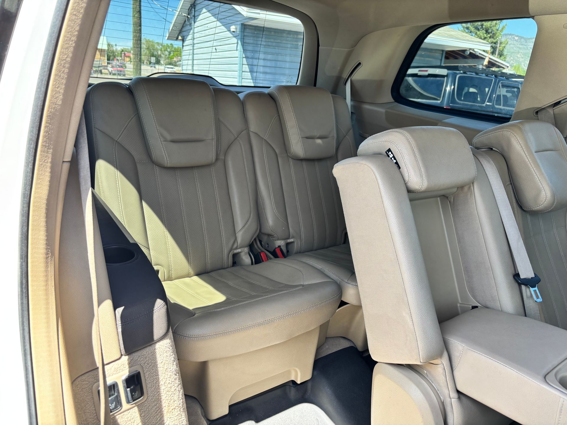 Car interior with beige and gray seats, viewed from the open side door.