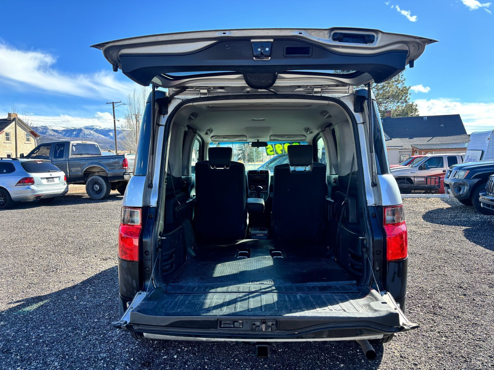Open rear of white van with empty cargo area in a parking lot