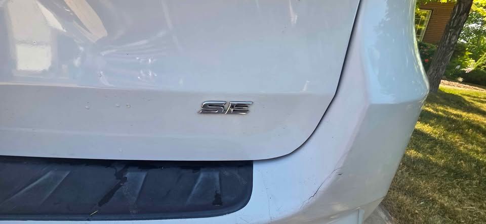 Close-up of a white car’s rear hatch with a small badge above the bumper.
