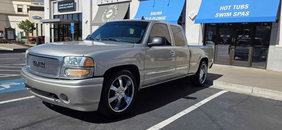 Silver pickup truck parked in front of shops on a sunny street