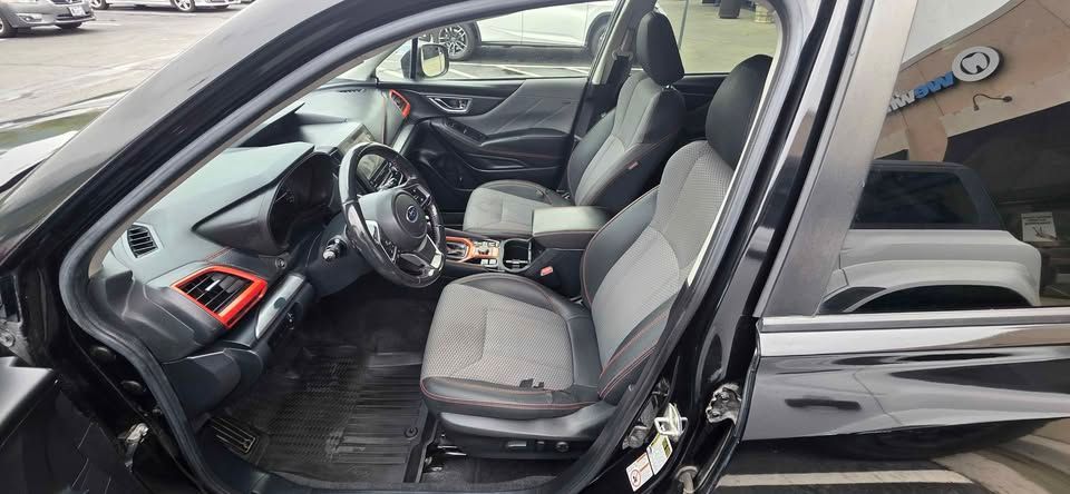 Open car door showing gray front seats and black dashboard with red trim