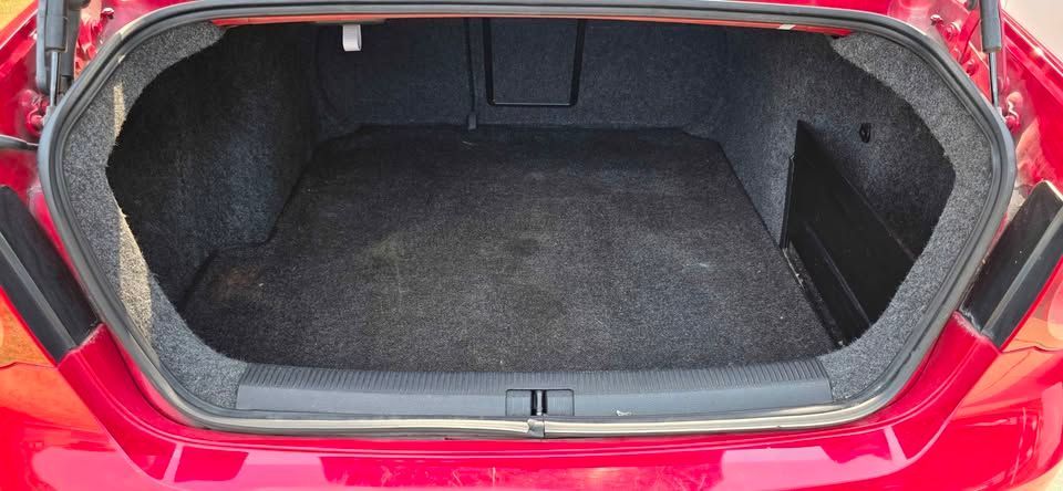 Open car trunk with black carpeted cargo space and red exterior frame