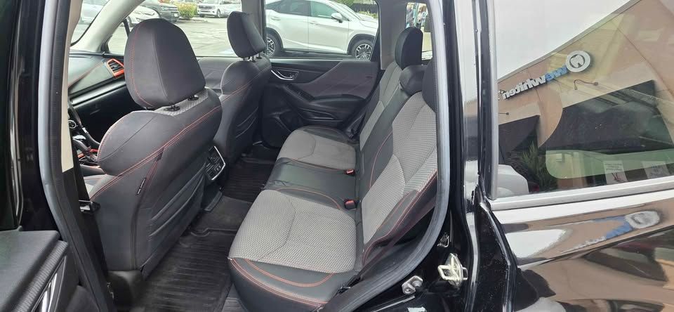 Car’s rear seat area with gray fabric seats and black trim, seen through the open door