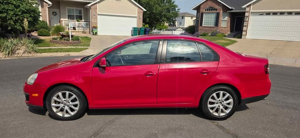 Red sedan parked on a residential street in front of houses and a driveway.