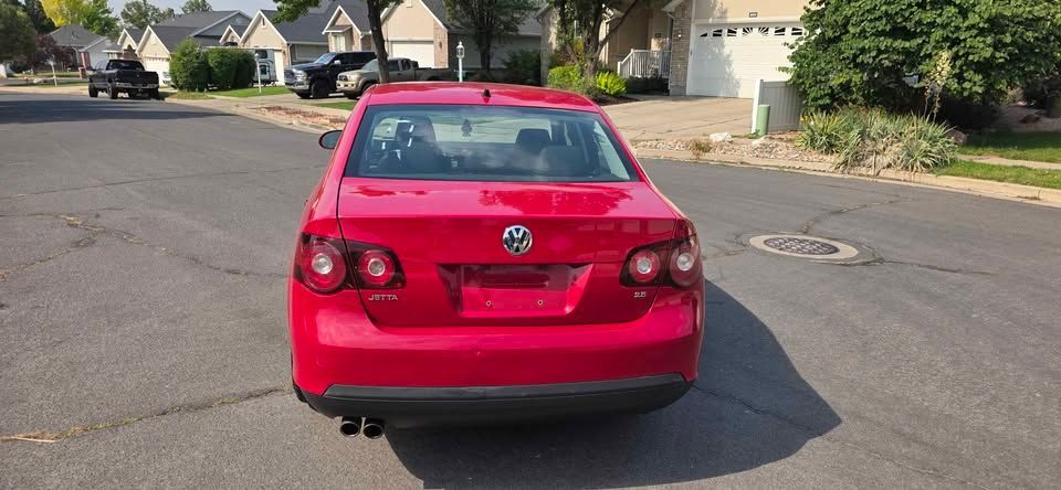 Red sedan parked on a suburban street, rear view