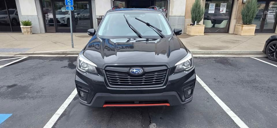 Black car parked in a marked space outside a storefront, front view