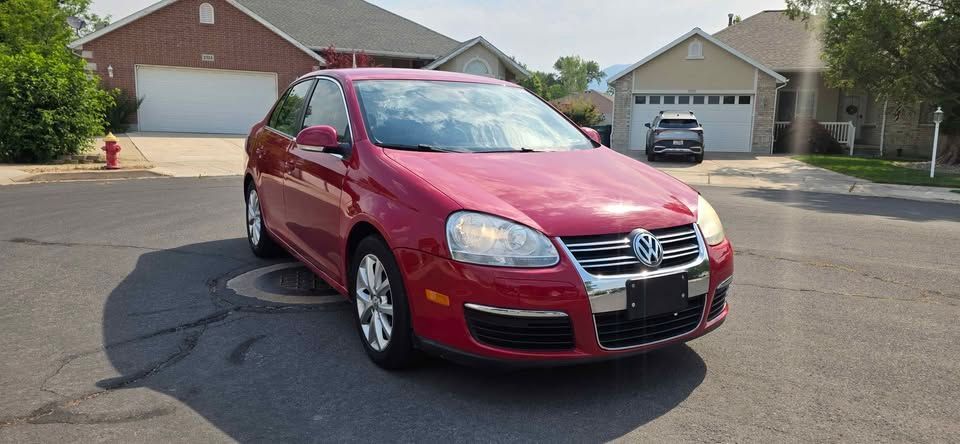 Red Volkswagen sedan parked on a suburban street in front of houses.