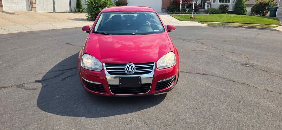 Red Volkswagen sedan parked on a street, front view.