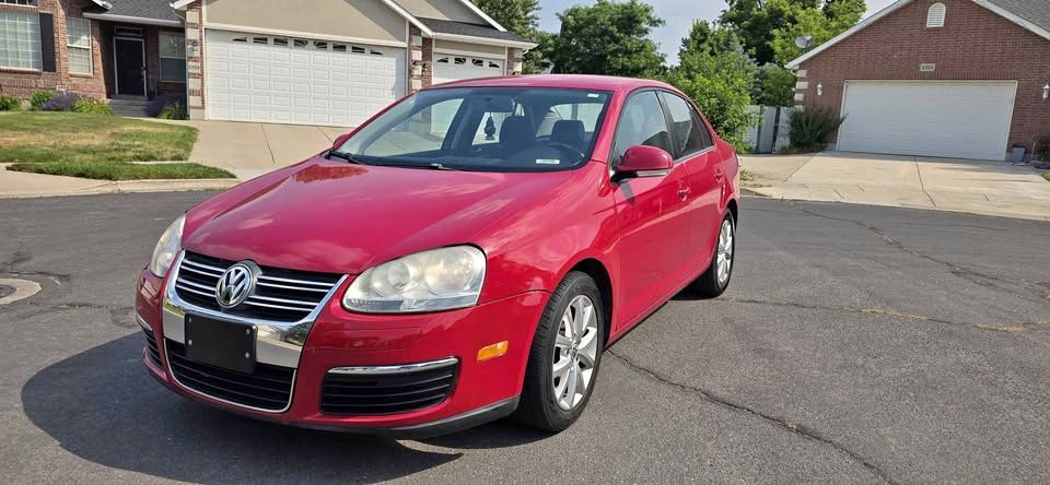 Red sedan parked on a suburban street in front of houses and garages
