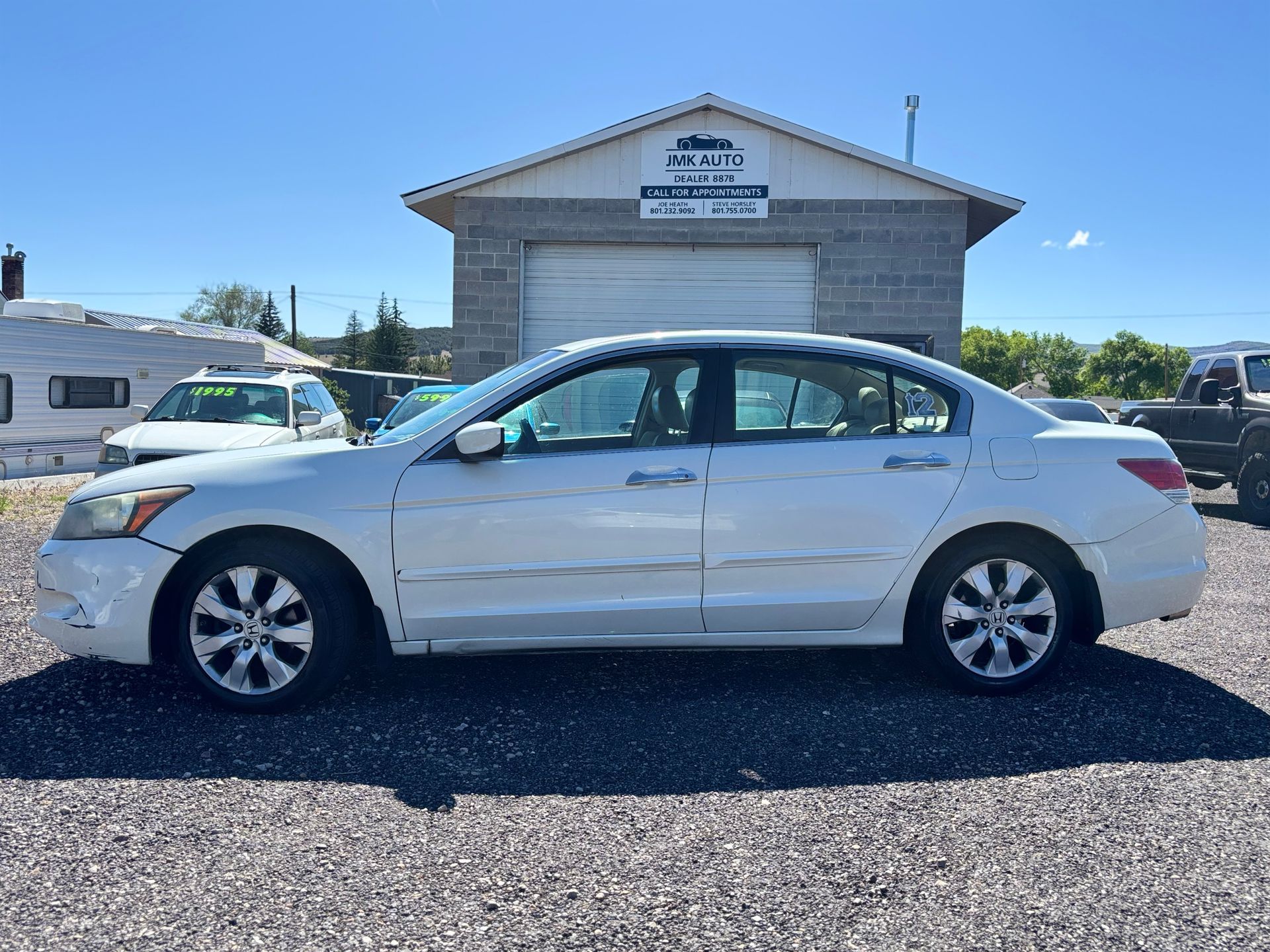 White sedan parked in front of a building under a clear blue sky