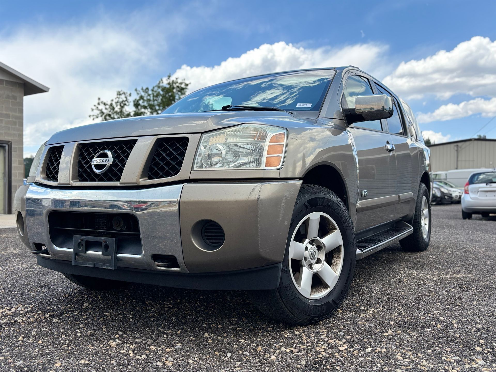 Silver Nissan SUV parked on gravel under a partly cloudy sky