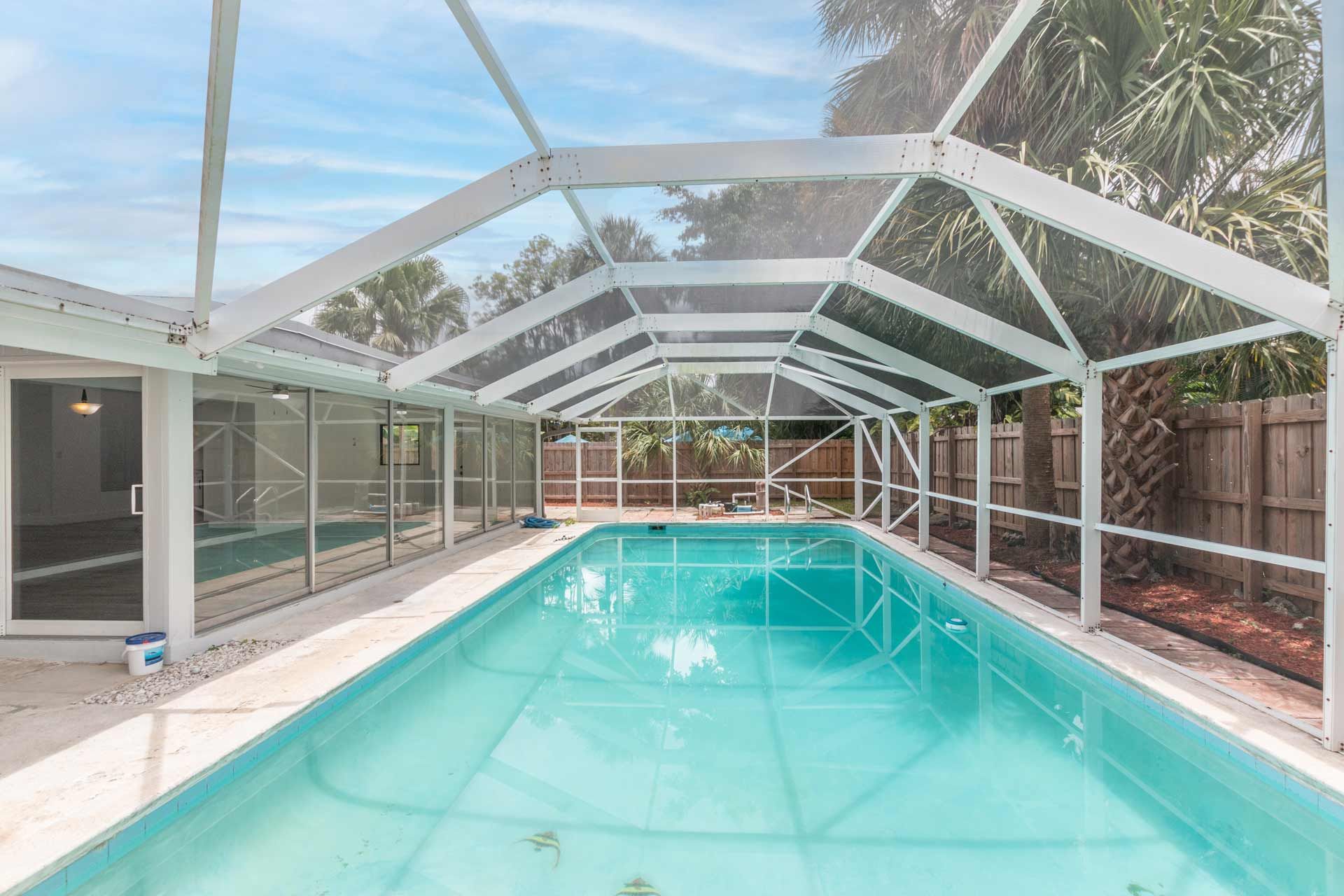 A rectangular pool with clear blue water, screened enclosure
