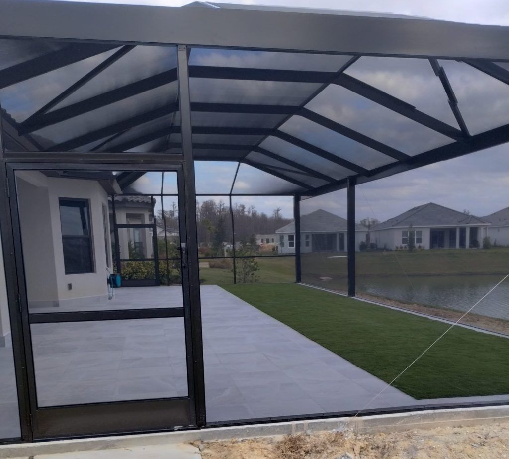 Screened patio with dark frame, overlooking a lawn and water feature.